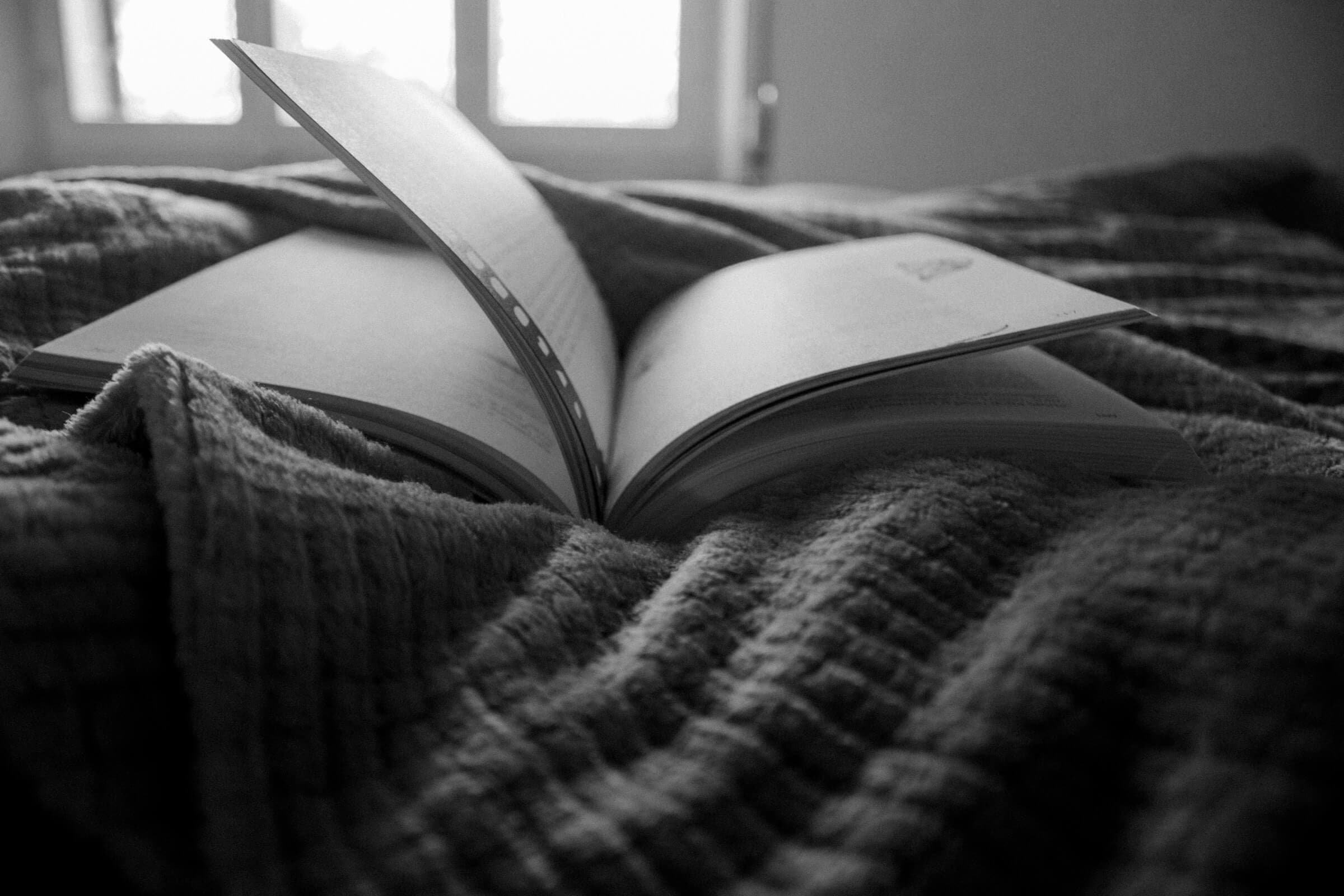 A photo of an opened book on a comfortable blanket