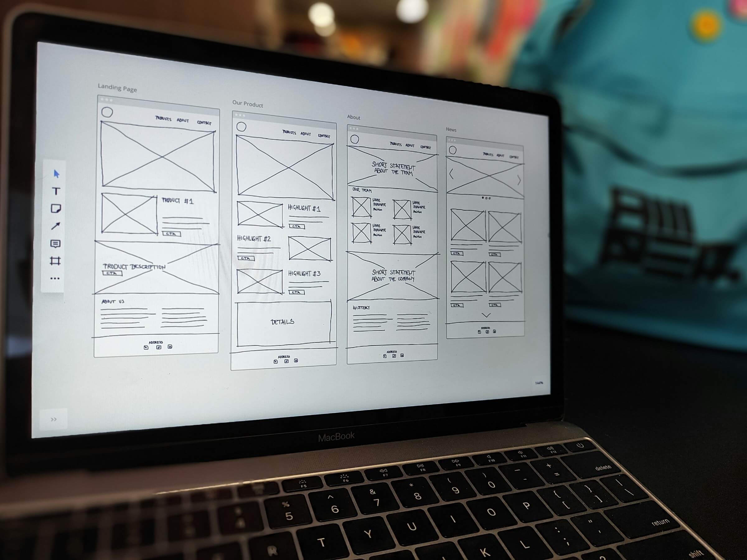 A photo of a laptop with design wireframes on the screen